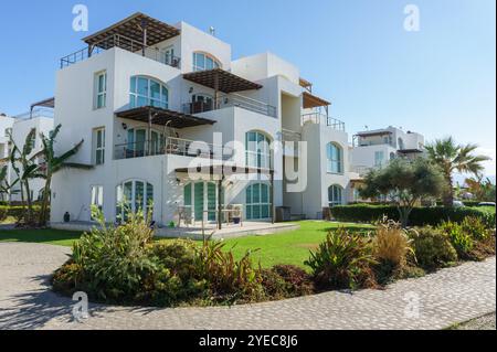 Un'elegante villa costiera e' circondata da vivaci giardini e palme sotto un cielo azzurro. Foto Stock