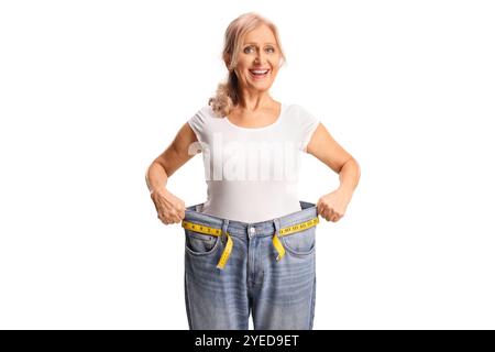 Felice donna di mezza età che prova un paio di jeans, concetto di perdita di peso isolato su sfondo bianco Foto Stock