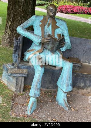 Scultura dell'uomo che legge su Park Bench Foto Stock