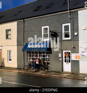 Donna bionda all'Harry's Café sulla High Street e sulla strada principale che attraversa Cowbridge, vale of Glamorgan, Galles del Sud, Regno Unito. Ottobre 2024. Autunno Foto Stock