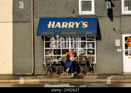 Donna bionda all'Harry's Café sulla High Street e sulla strada principale che attraversa Cowbridge, vale of Glamorgan, Galles del Sud, Regno Unito. Ottobre 2024. Autunno Foto Stock