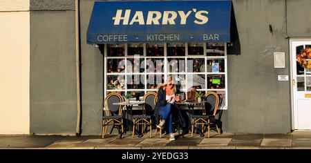 Donna bionda all'Harry's Café sulla High Street e sulla strada principale che attraversa Cowbridge, vale of Glamorgan, Galles del Sud, Regno Unito. Ottobre 2024. Autunno Foto Stock