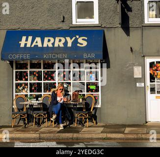 Donna bionda all'Harry's Café sulla High Street e sulla strada principale che attraversa Cowbridge, vale of Glamorgan, Galles del Sud, Regno Unito. Ottobre 2024. Autunno Foto Stock