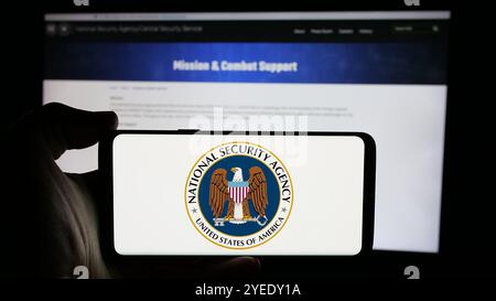 Persona che detiene un cellulare con il logo dell'Agenzia nazionale per la sicurezza (NSA) sullo schermo davanti alla pagina web. Mettere a fuoco il display del telefono. Foto Stock