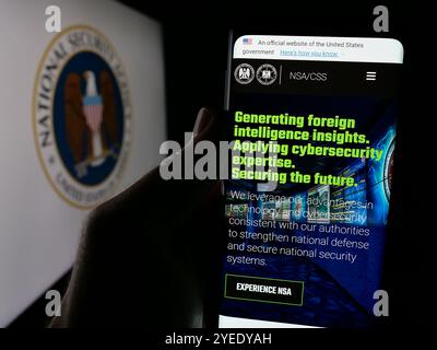 Persona che detiene un cellulare con la pagina web dell'Agenzia nazionale di sicurezza (NSA) sullo schermo davanti al logo. Messa a fuoco al centro del display del telefono. Foto Stock