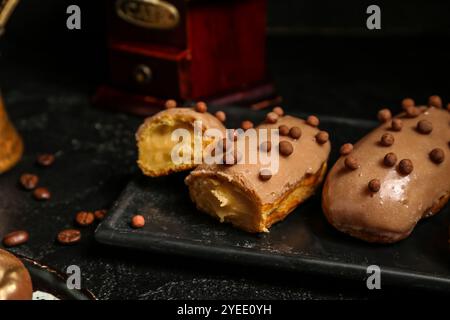 Piatto con eclari dolci su sfondo scuro, primo piano Foto Stock