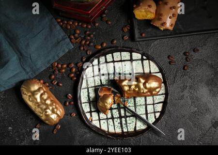 Composizione con eclari dolci e chicchi di caffè su sfondo scuro Foto Stock