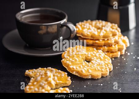 Biscotti dolci a forma di fiore. Gustosi biscotti su un tavolo nero. Foto Stock