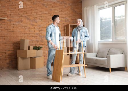 Felice coppia musulmana che assembla un ripiano a casa Foto Stock