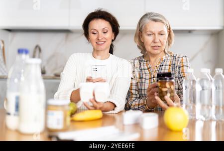 Due donne che scansionano prodotti diversi utilizzando il proprio smartphone Foto Stock