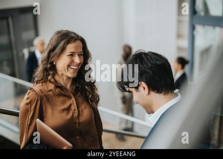 Donna d'affari felice e matura che parla con un giovane collega maschio Foto Stock
