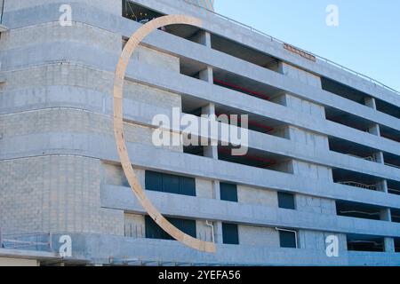 Parcheggio in cemento a più piani in costruzione con una curva a forma di C in compensato su un lato. Giorno di sole, nessuno copia spazio. Foto Stock