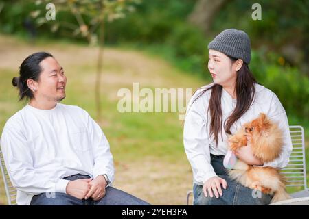 Un uomo coreano e una donna giapponese, entrambi di 30 anni e una coppia sposata, stanno godendo un brunch autunnale con tre cani in un elegante caffè situato in Foto Stock