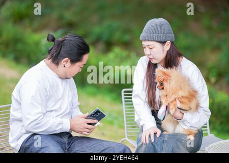 Un uomo coreano e una donna giapponese, entrambi di 30 anni e una coppia sposata, stanno godendo un brunch autunnale con tre cani in un elegante caffè situato in Foto Stock