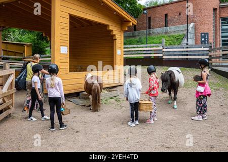 Bambini nella stalla di pony ponitouhut di Tallipihan nei cantieri stalla, Tampere, Finlandia Foto Stock