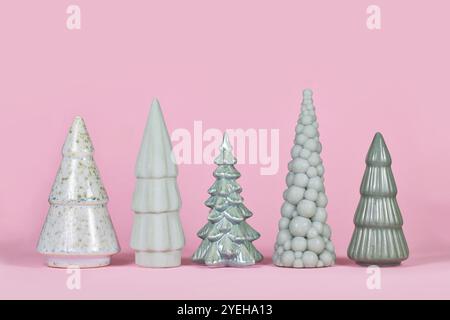 Alberi di Natale in ceramica verde chiaro di diversa forma su sfondo rosa Foto Stock