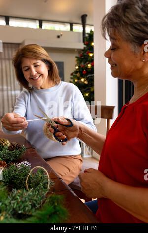 Creare decorazioni natalizie, amici donne anziane che condividono lo spirito natalizio, a casa Foto Stock