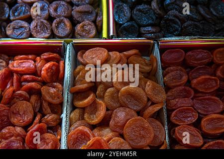 Arancia e albicocche secche scure in scatole per la vendita sul mercato, vista dall'alto. Frutta secca, albicocche secche come sfondo. Foto Stock