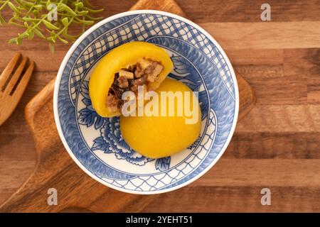 Panino di patate dolci fatto in casa con carne di maiale macinata, funghi e farciture di bambù tritate all'interno in una ciotola su fondo di legno. Foto Stock