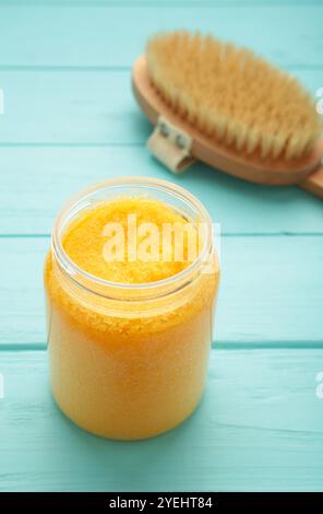 Pasta di zucchero fatta a mano con olio di Argan. Strofinare con la spazzola massaggiante su sfondo blu. Vista dall'alto Foto Stock