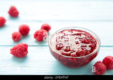 Marmellata di lamponi in un recipiente con frutti di bosco su sfondo blu di legno. Vista dall'alto Foto Stock