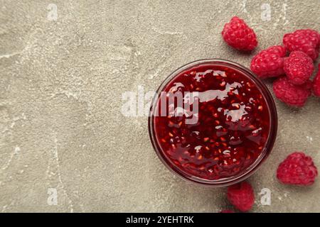 Marmellata di lamponi nel recipiente con frutti di bosco su sfondo grigio di cemento. Vista dall'alto Foto Stock