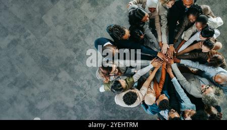 Vista dall'alto di un team aziendale eterogeneo con colleghi che mettono le mani insieme, simboleggiando l'unità, il lavoro di squadra e la collaborazione. Foto Stock