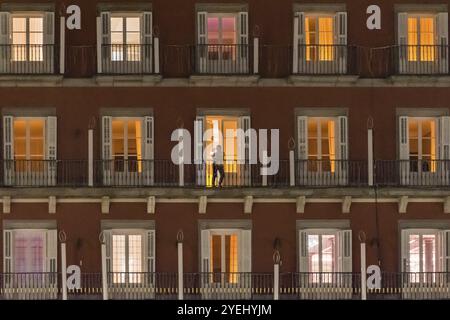 Una vista notturna di un condominio con finestre illuminate e una persona in piedi su un balcone, Plaza Mayor, Madrid, Spagna, Europa Foto Stock