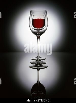 3 bicchieri da vino rossi su sfondo riflettente Foto Stock