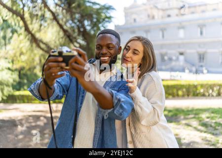 Simpatica coppia multietnica che scatta selfie con la fotocamera digitale in un punto panoramico della città Foto Stock