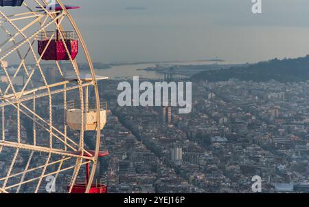 Ruota panoramica che si affaccia su una città e sull'oceano sotto un caldo tramonto, vista di Barcellona da Tibidabo, Barcellona, Catalogna, Spagna, Europa Foto Stock