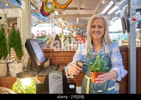 donna cassiera che sta scansionando un codice a barre Foto Stock