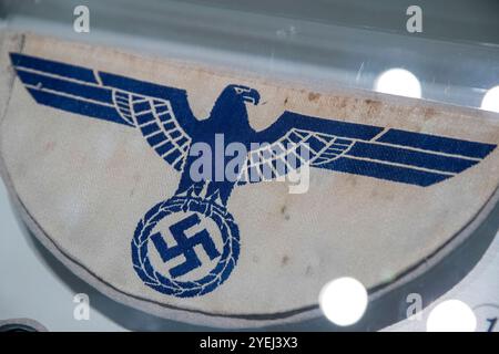 Primo piano di un'insegna di stoffa tedesca della seconda guerra mondiale con un'aquila blu che regge una svastica, stampata su uno sfondo in tessuto sbiadito. Foto Stock
