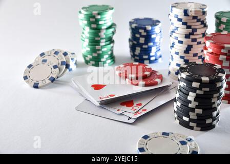 Mazzo di carte e pile di patatine per scommettere isolate su un tavolo bianco. Vista rialzata. Foto Stock