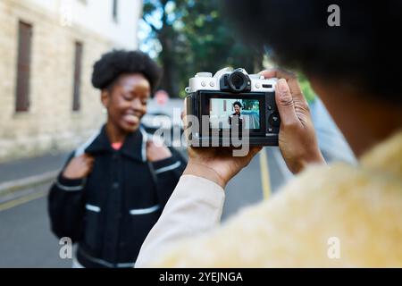 Giovane donna che posa per una foto di strada scattata con una fotocamera digitale in ambiente urbano Foto Stock