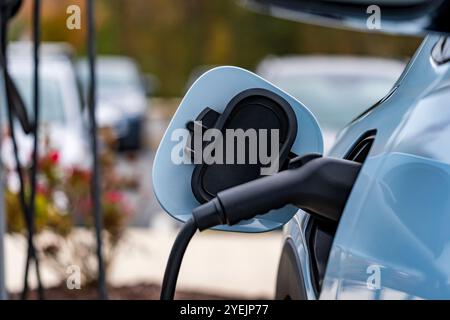 Un veicolo elettrico si ricarica in una stazione mentre il proprietario è al lavoro, consentendo una batteria completamente carica al momento del ritorno. Questa configurazione massima Foto Stock