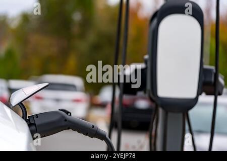 Un veicolo elettrico si ricarica in una stazione mentre il proprietario è al lavoro, consentendo una batteria completamente carica al momento del ritorno. Questa configurazione massima Foto Stock