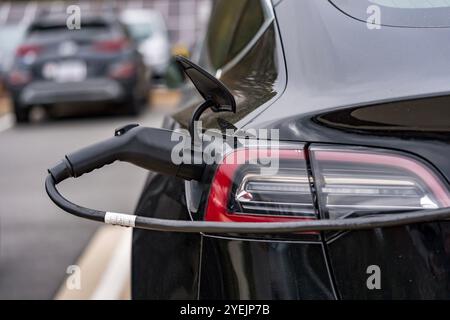 Un veicolo elettrico si ricarica in una stazione mentre il proprietario è al lavoro, consentendo una batteria completamente carica al momento del ritorno. Questa configurazione massima Foto Stock