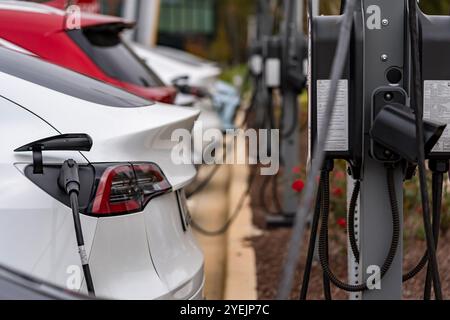 Un veicolo elettrico si ricarica in una stazione mentre il proprietario è al lavoro, consentendo una batteria completamente carica al momento del ritorno. Questa configurazione massima Foto Stock