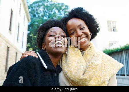 Amici gioiosi che abbracciano la città in un giorno luminoso, irradiando felicità e connessione Foto Stock