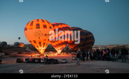 Le colorate mongolfiere salgono nel cielo della mattina presto in Cappadocia mentre gli spettatori si riuniscono per assistere al lancio mozzafiato Foto Stock