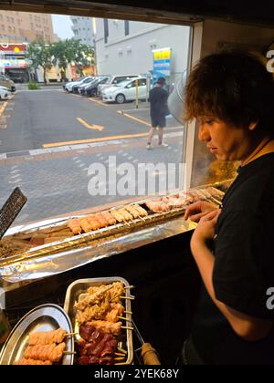 Un giovane giapponese che grigia spiedini al ristorante Washio Yakitori Izakaya a Chuocho, Kagoshima, Giappone. Foto Stock