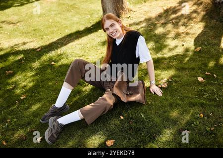 Questo giovane sorride in modo luminoso, rilassandosi comodamente sull'erba in un parco soleggiato. Foto Stock