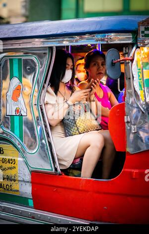 Donne e passeggeri filippini sedevano a bordo di una jeepney a Manila, nelle Filippine. Foto Stock