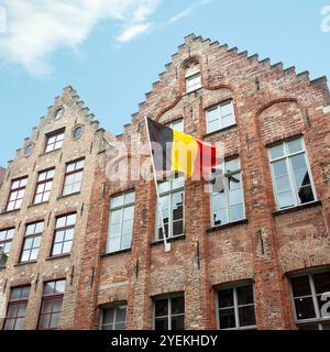 Bandiera nazionale belga che sventola sulla facciata di un vecchio edificio nella città vecchia Foto Stock