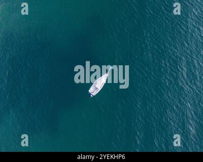 Solitaria barca a vela che si sposta pacificamente nelle vaste acque dell'Oceano aperto Foto Stock