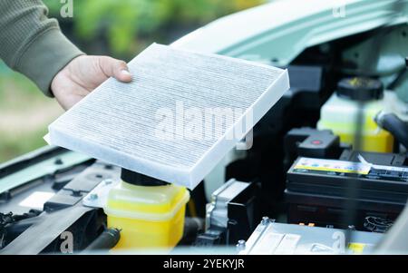 Il proprietario di un'auto è in possesso di un filtro dell'aria per l'esame. L'importanza dell'ispezione, della pulizia e della sostituzione regolari dei filtri dell'aria dell'auto sottolinea la manutenzione Foto Stock