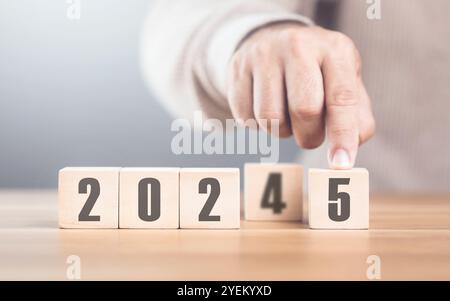 Hand sostituisce "2024" con "2025" utilizzando blocchi numerici, simboleggiando la transizione verso il nuovo anno, rappresentando il cambiamento, il progresso e i PA in corso Foto Stock