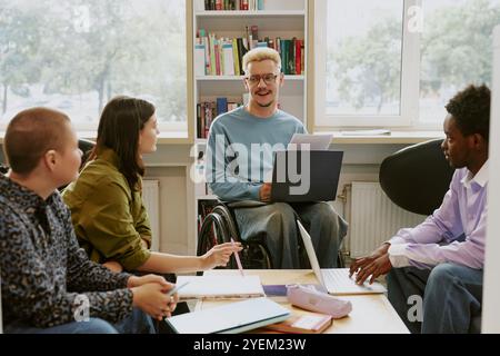 Gruppo di quattro diversi colleghi che discutono della strategia aziendale in ufficio con notebook e documenti, promuovendo la collaborazione e l'inclusione dei team Foto Stock