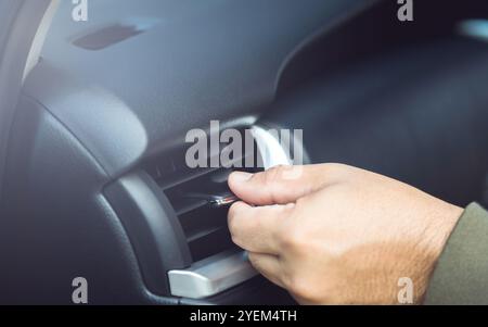 Il proprietario di un'auto regola manualmente la direzione della presa d'aria, garantendo un flusso d'aria ottimale all'interno del veicolo. Manutenzione corretta del veicolo e aria condizionata corretta Foto Stock